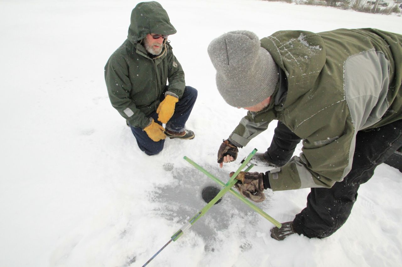 Two men ice fish on the ice. 