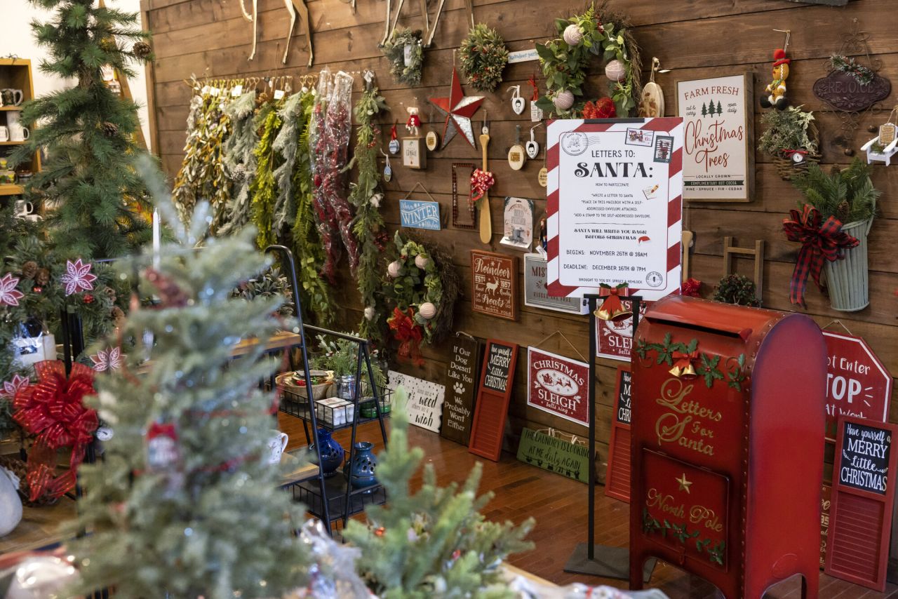A store display is crowded with Christmas decorations, a mailbox for letters to Santa, and more decor.