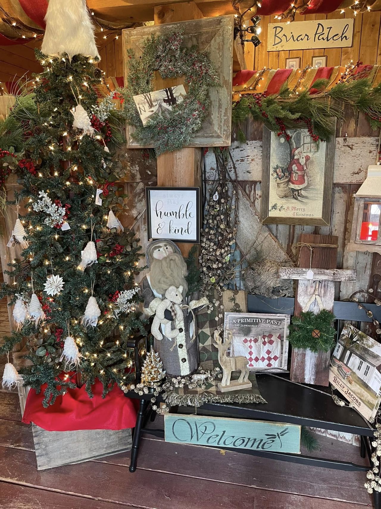 A store display of decorated Christmas tree, holiday-themed signs, and gifts.