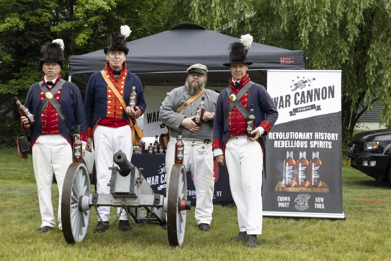 A group of soldiers stand posing with bottles of whiskey at a sponsor tent for a race.