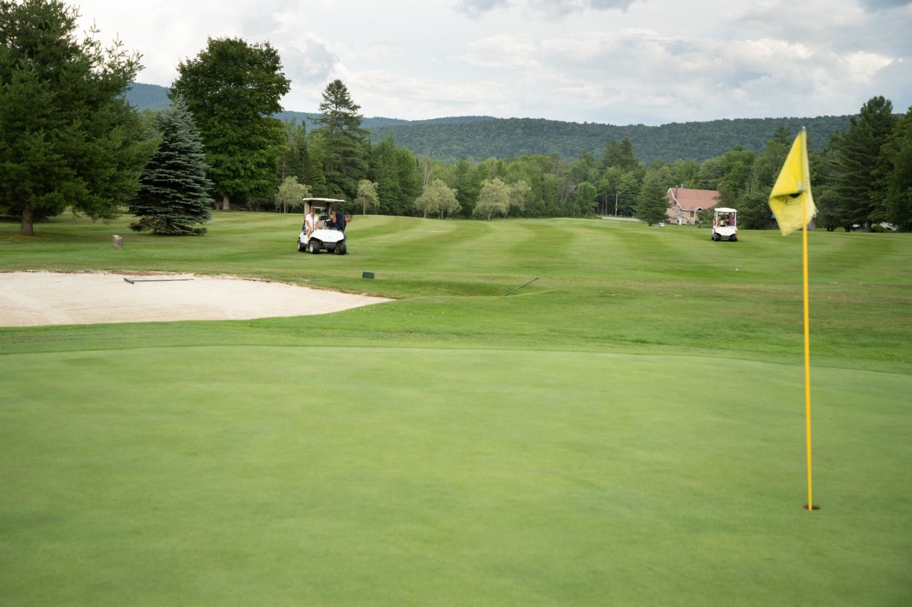 A green golf course with golf carts on the green. 