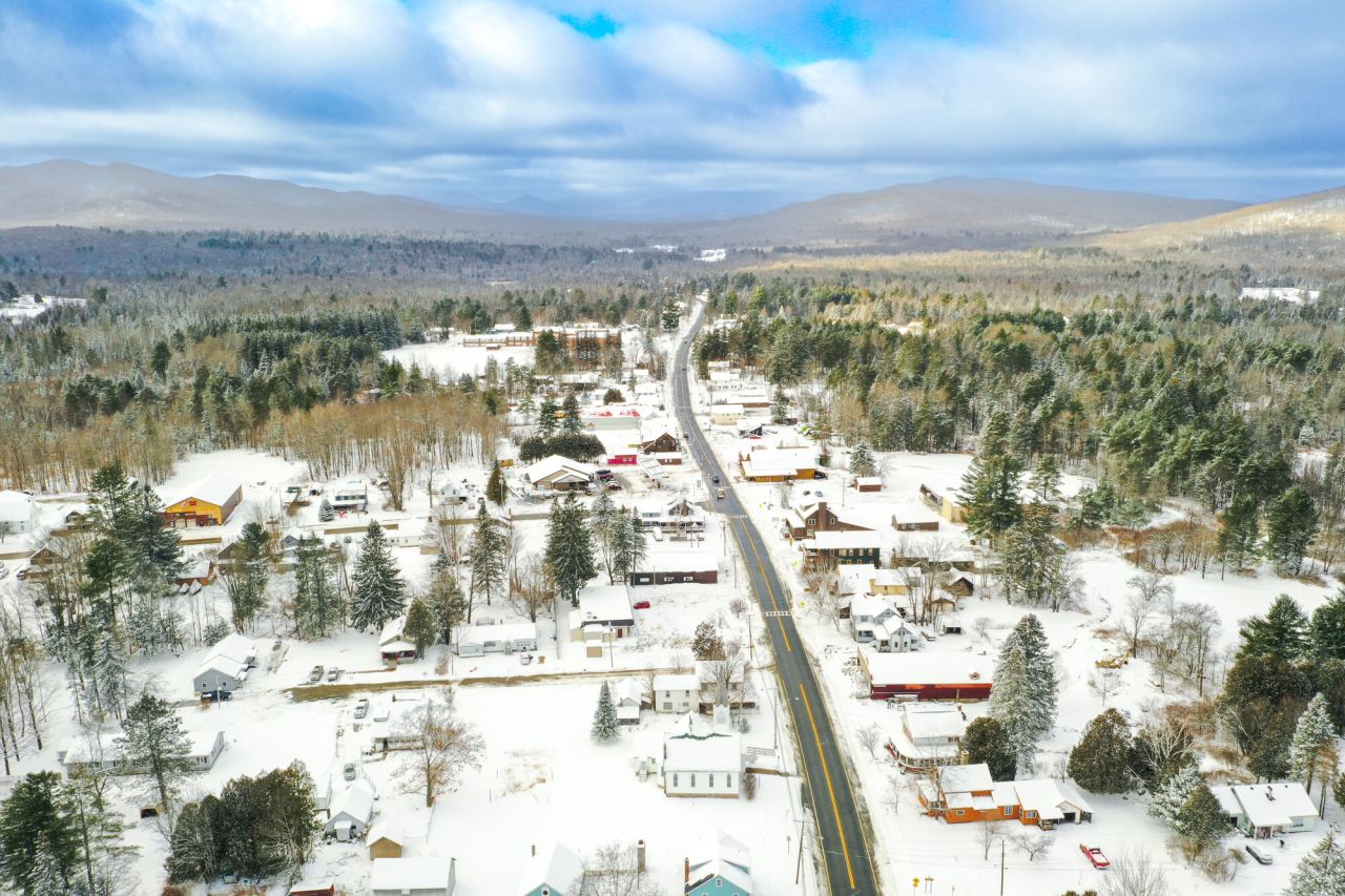An aerial view of a snowy mountain town with one main road cutting through. 