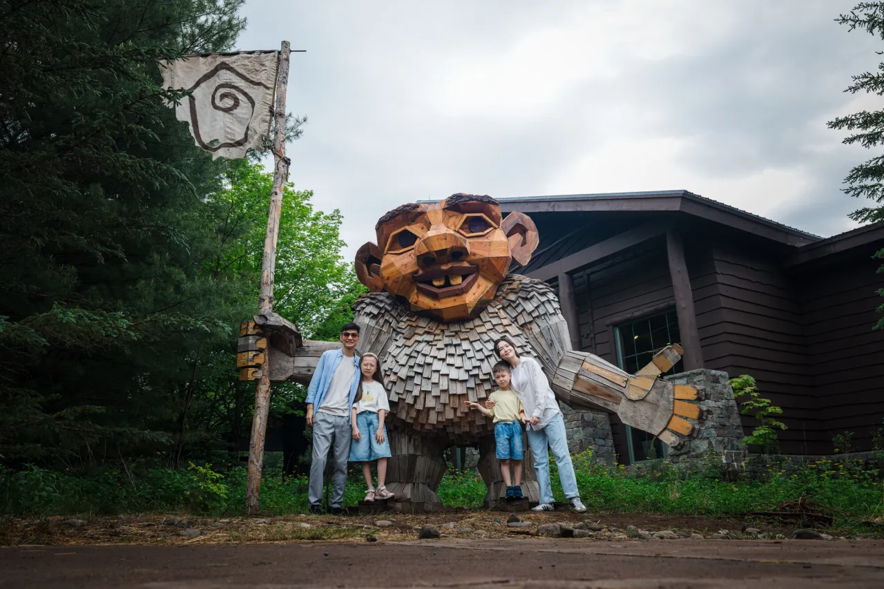 A family posing with a troll at The Wild Center.
