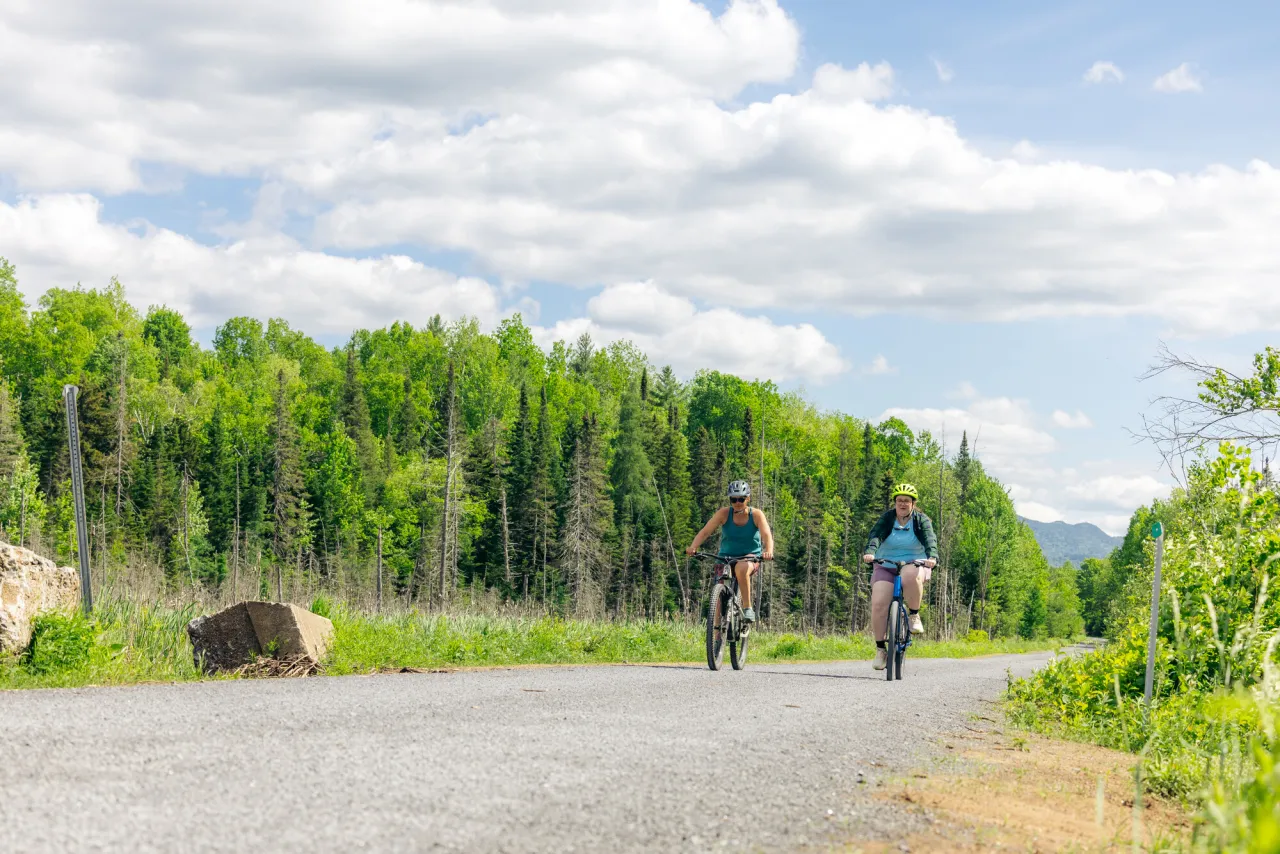 Two Cyclists ride on a packed gravel trail in spring. 