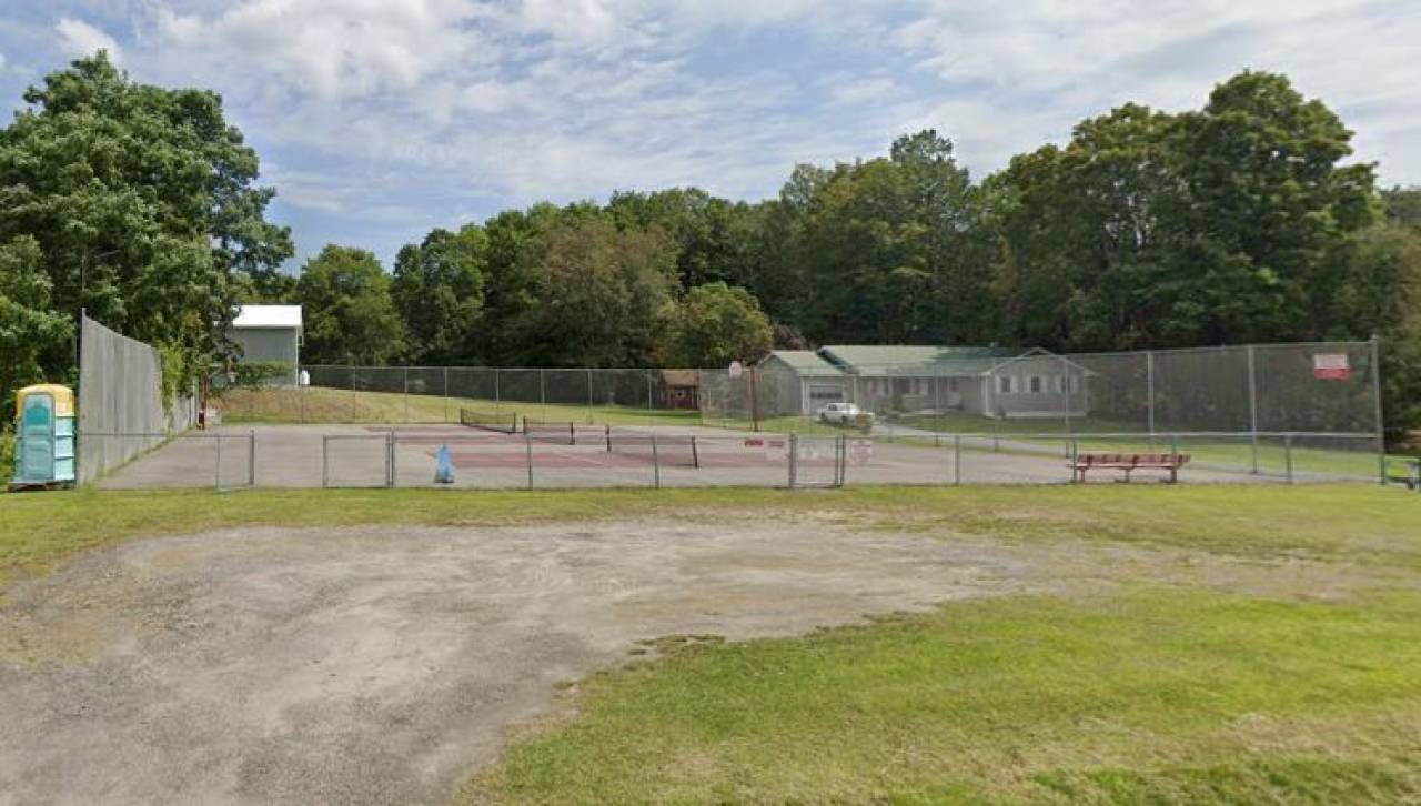 Three pickleball courts alongside a tennis court  at a local park. 