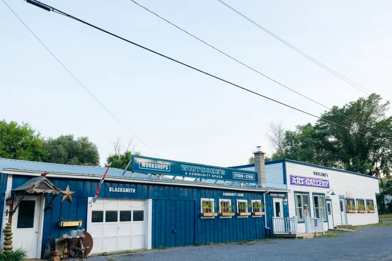 A blue garage attached to a white storefront for an art gallery and event space.