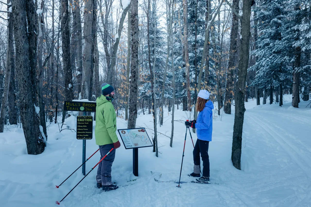a man and a woman with xc skis looking at a trailmap