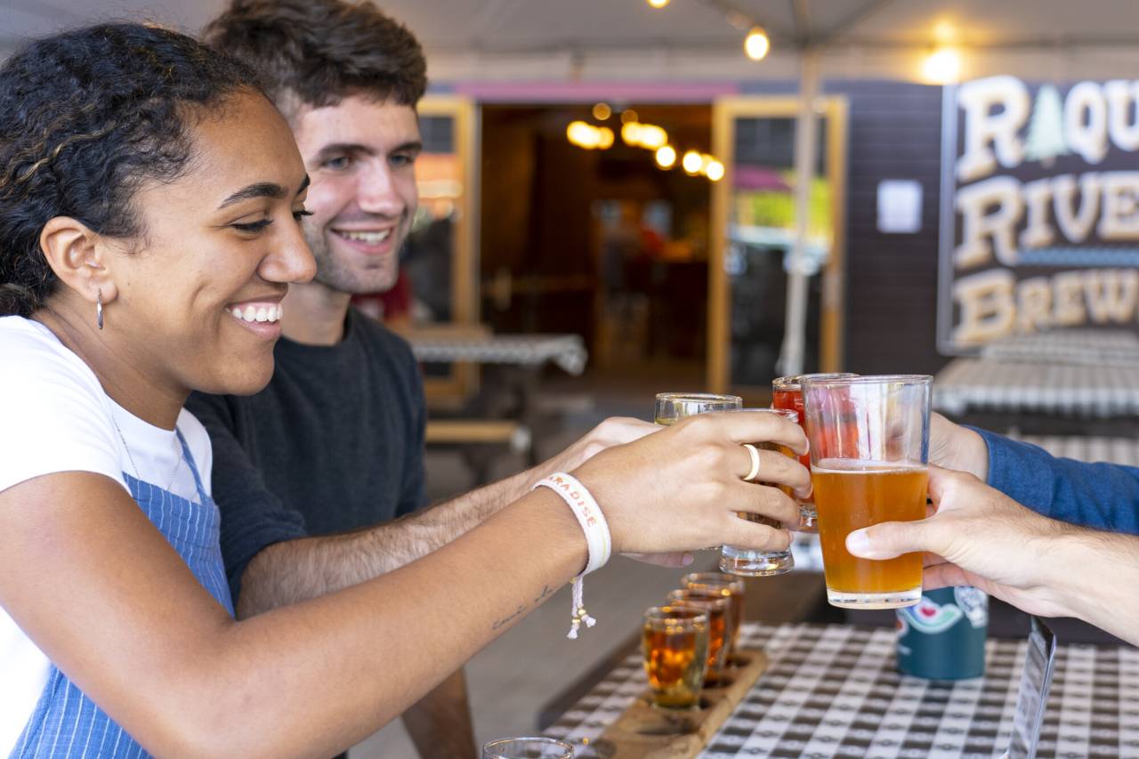 A man and woman cheers drinks at a picnic table.