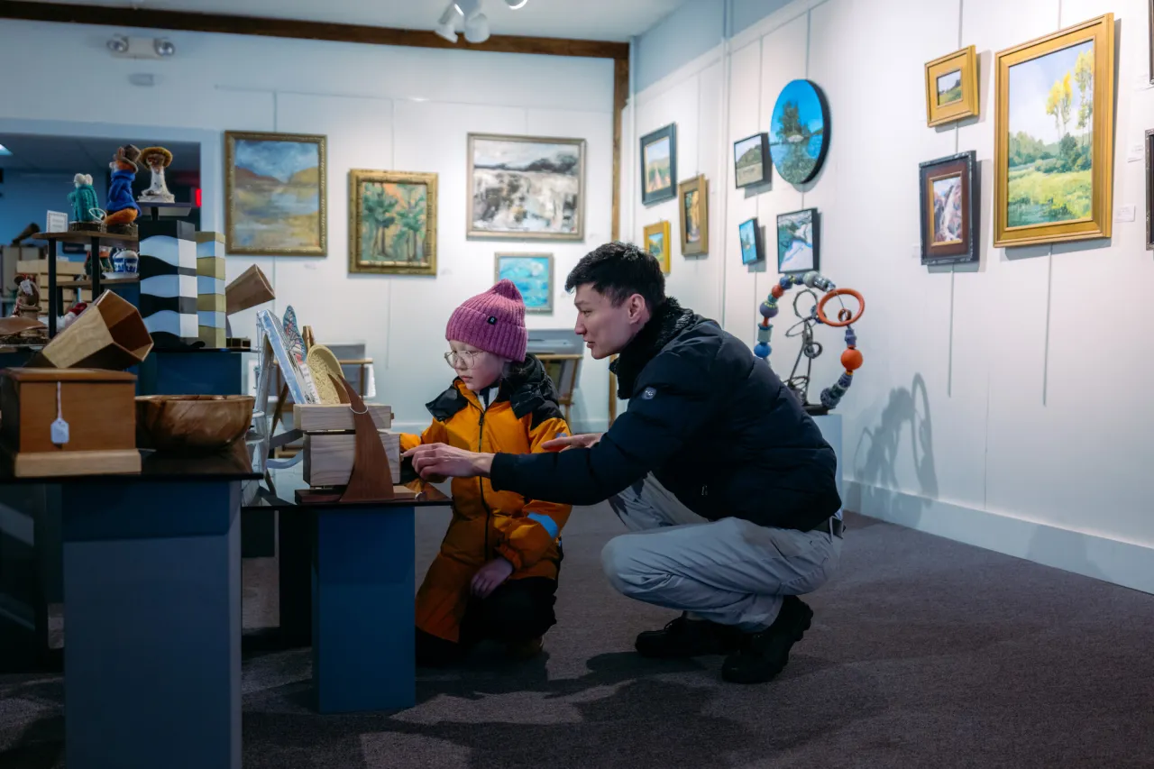 A man shows his child art at an art gallery.