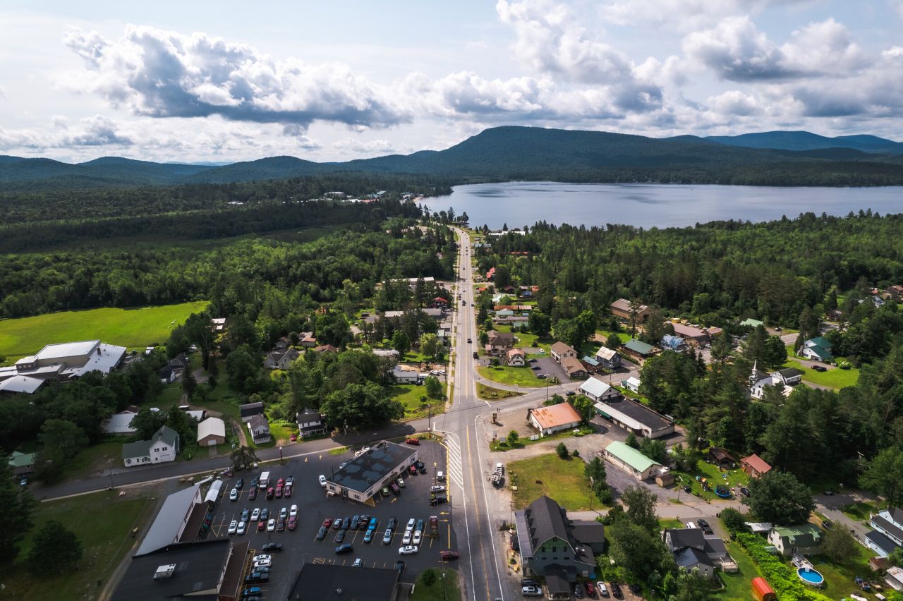 A road leading through a town alongside a lake,.