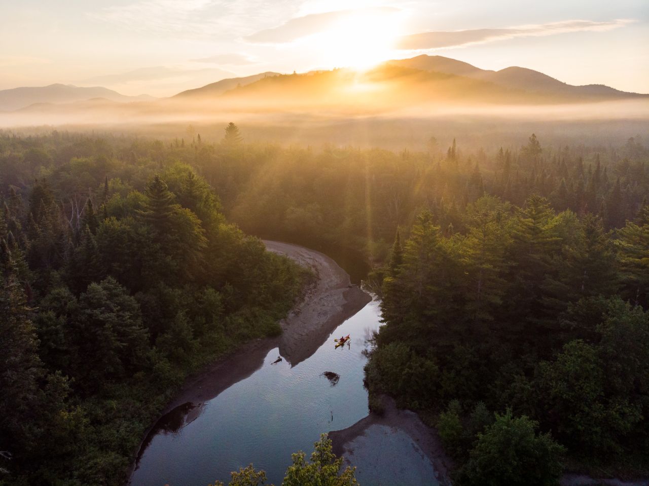 A mountain range at sunset over a river. 