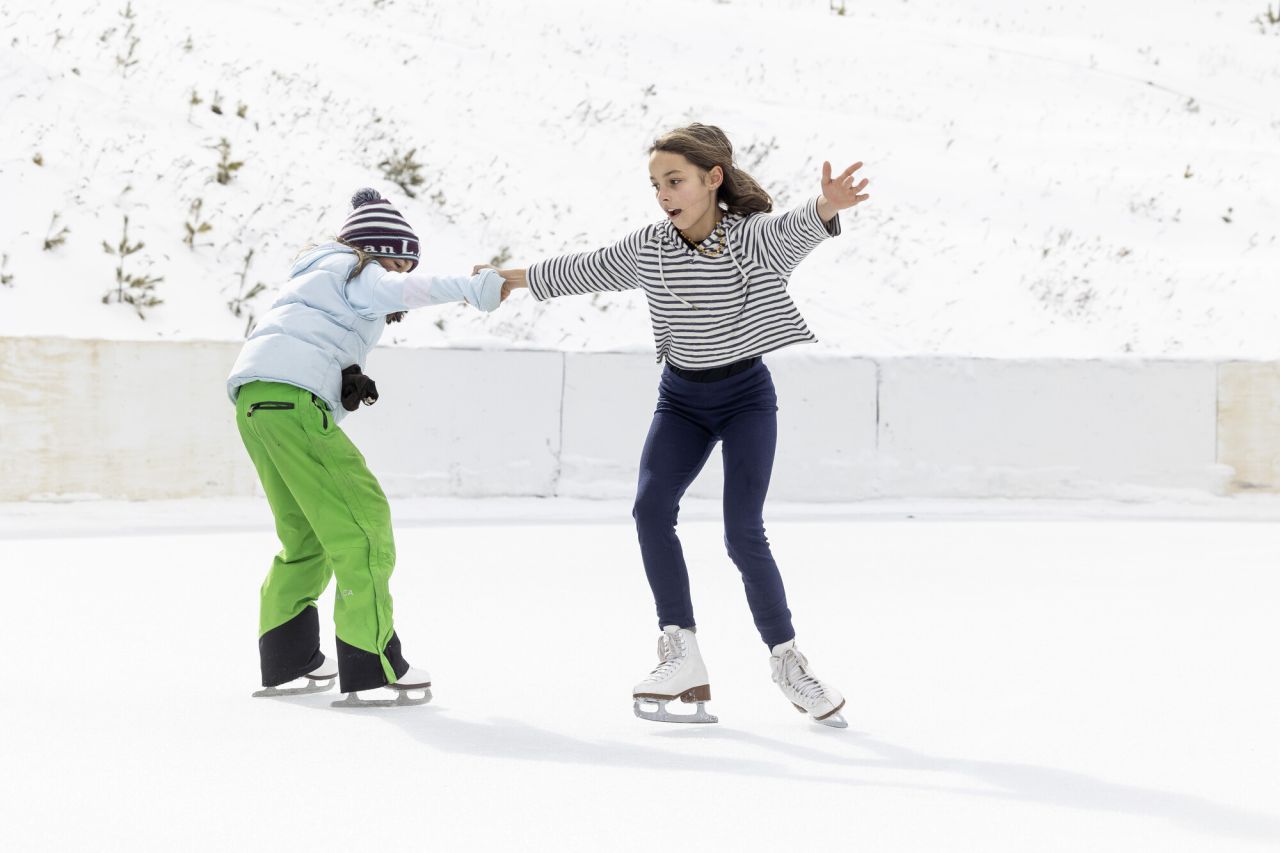 two young girls twirl on a ice skating rink in winter. 