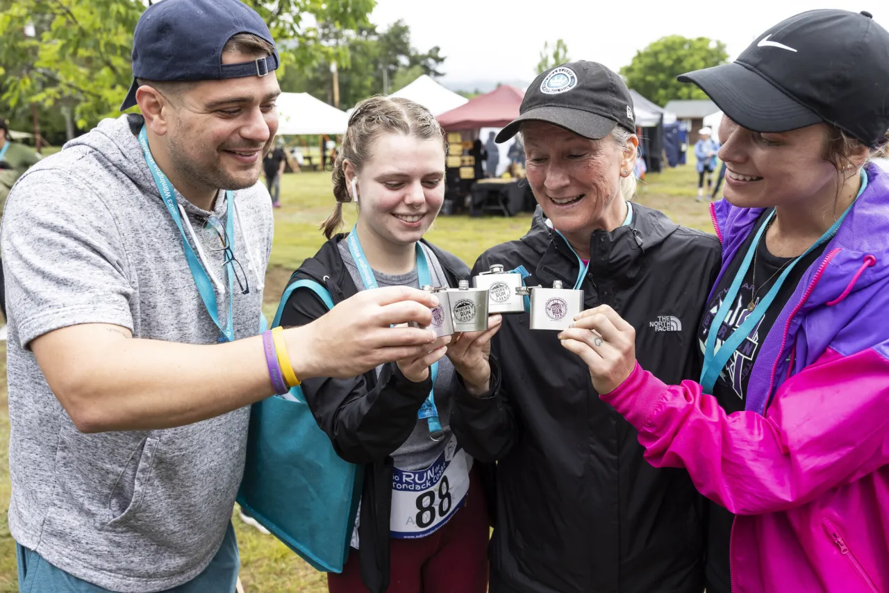 A group of runners drink flasks of whiskey at an outdoor event. 