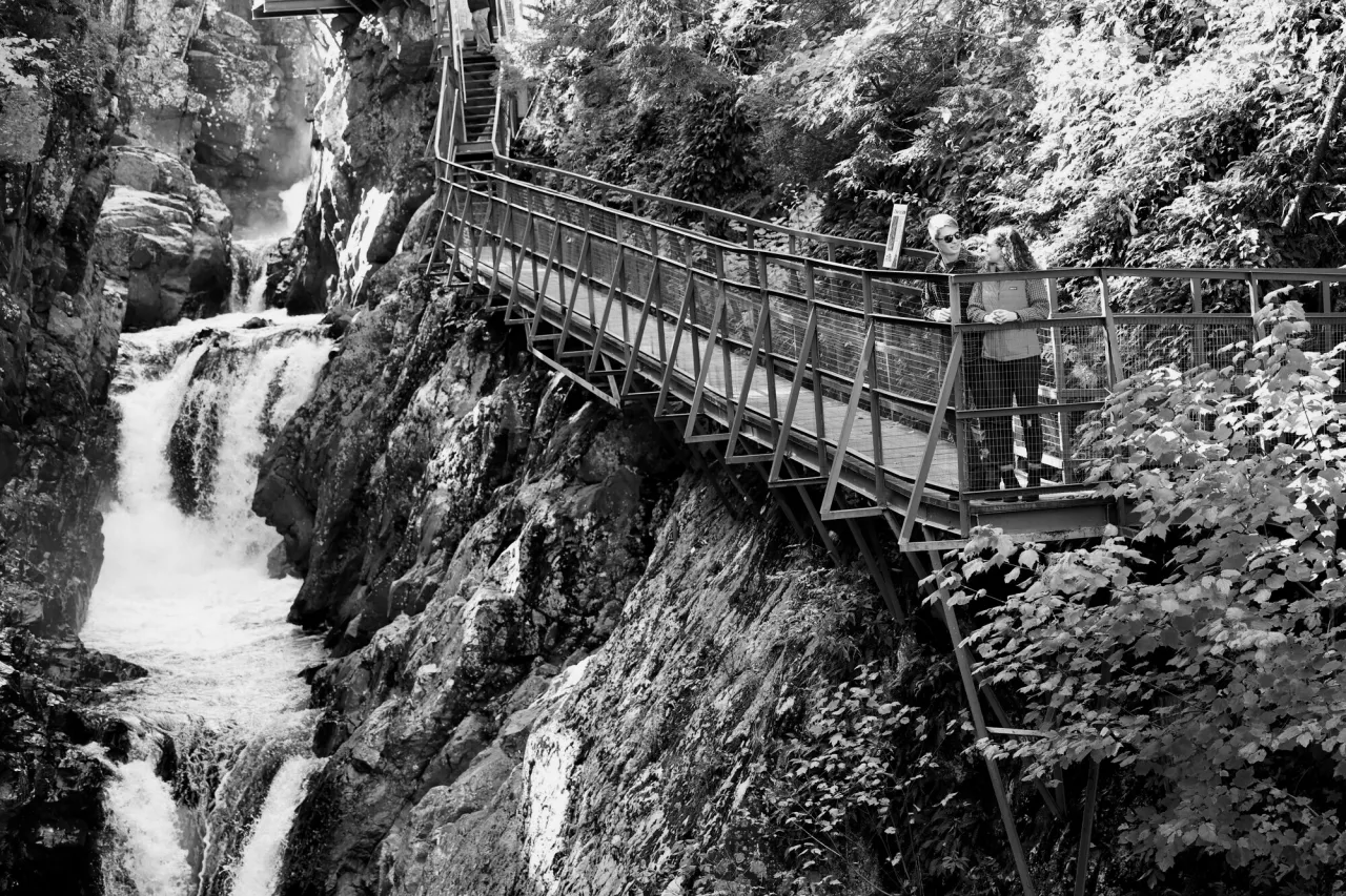 A man and woman on a narrow walkway in a rocky river gorge.