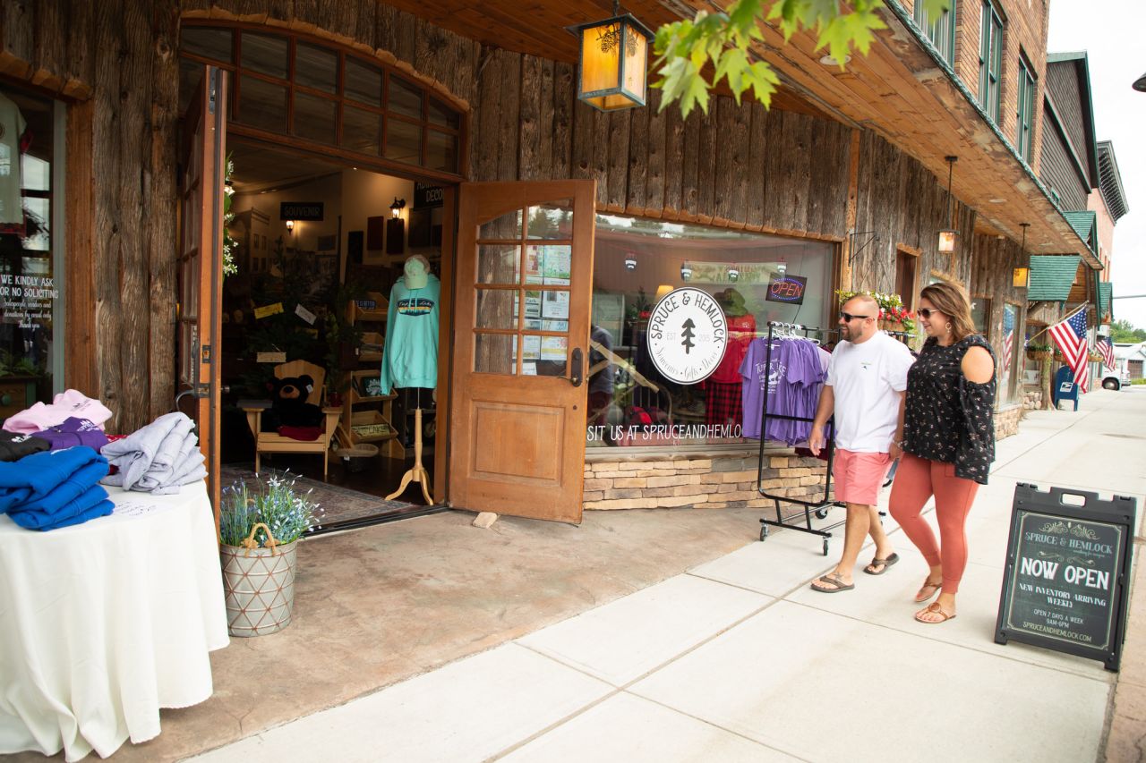 A man and woman walk into a boutique on a main street. 