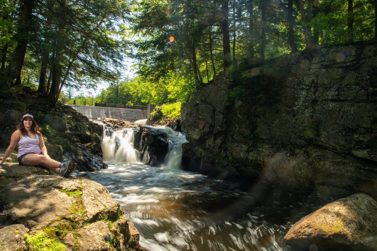 A woan sitting next to a waterfall