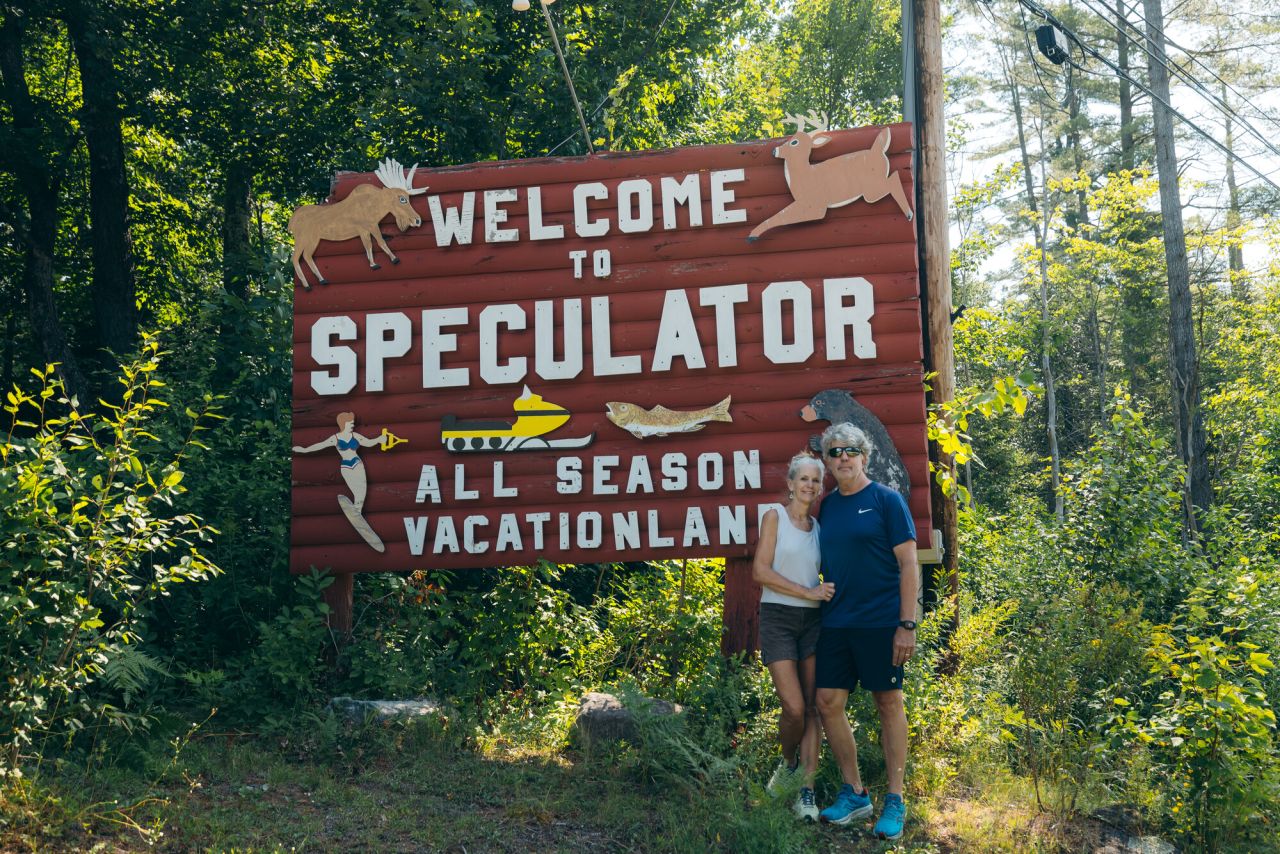 A couple posing in front of the Welcome to Speculator sign.