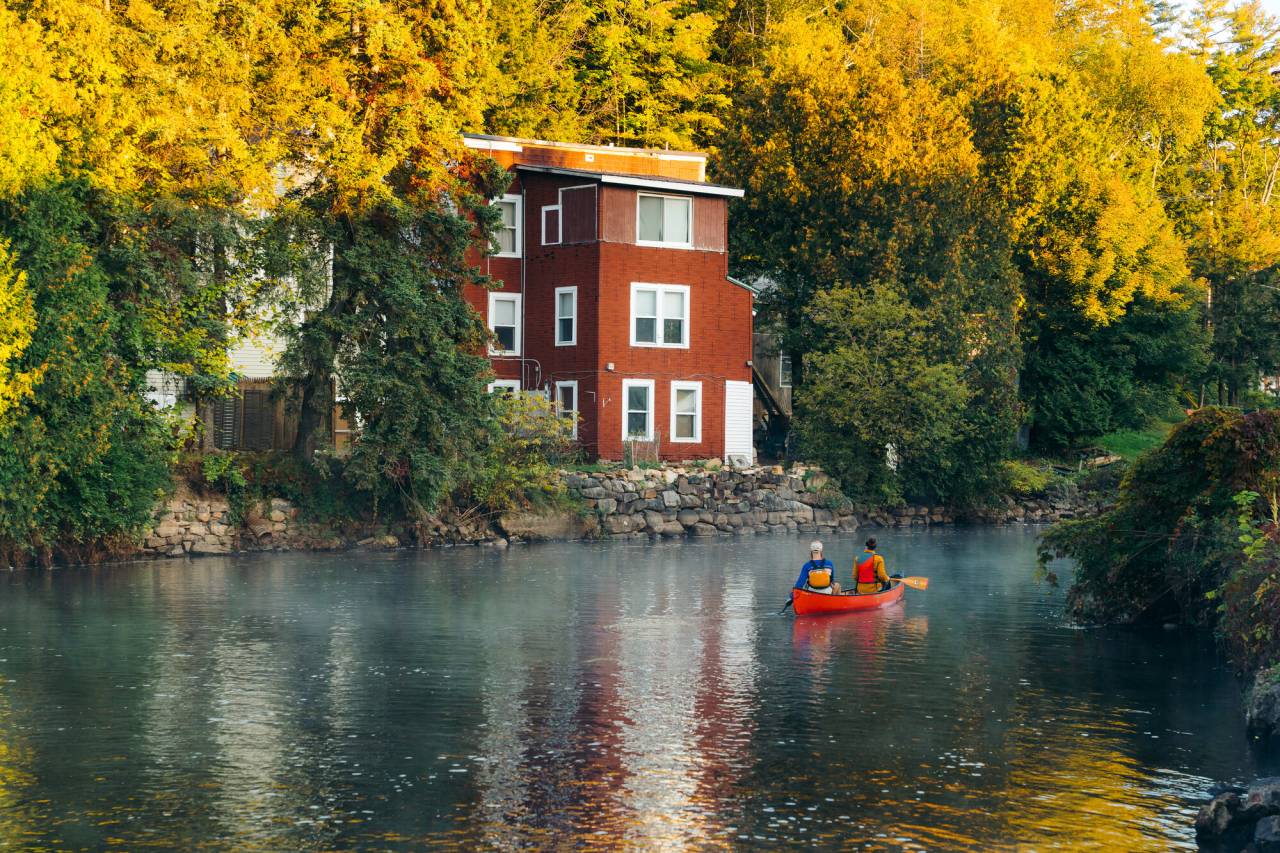 Two people paddling a canoe through Saranac Lake on the Saranac River.