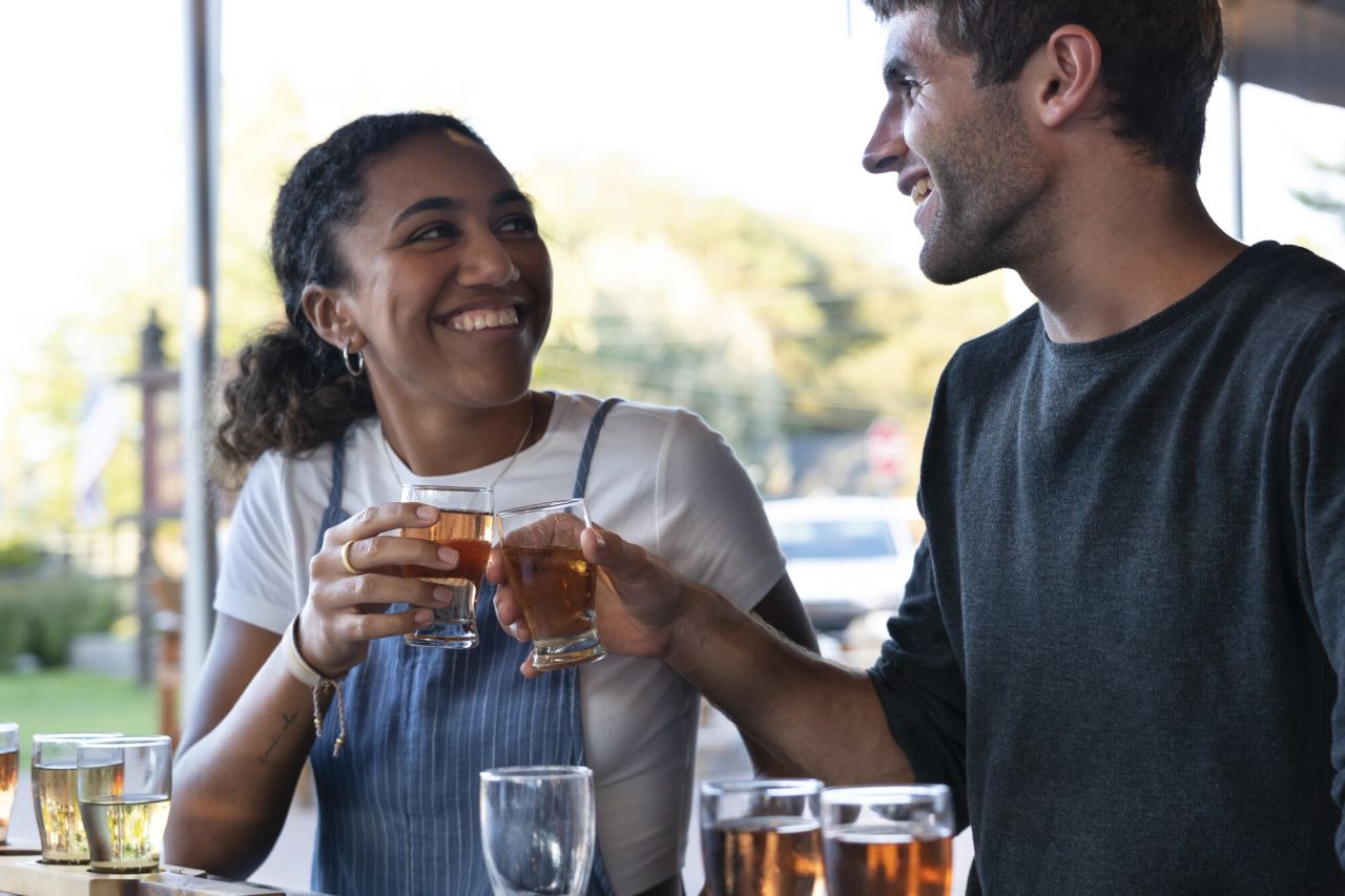A man and woman cheers drinks together. 