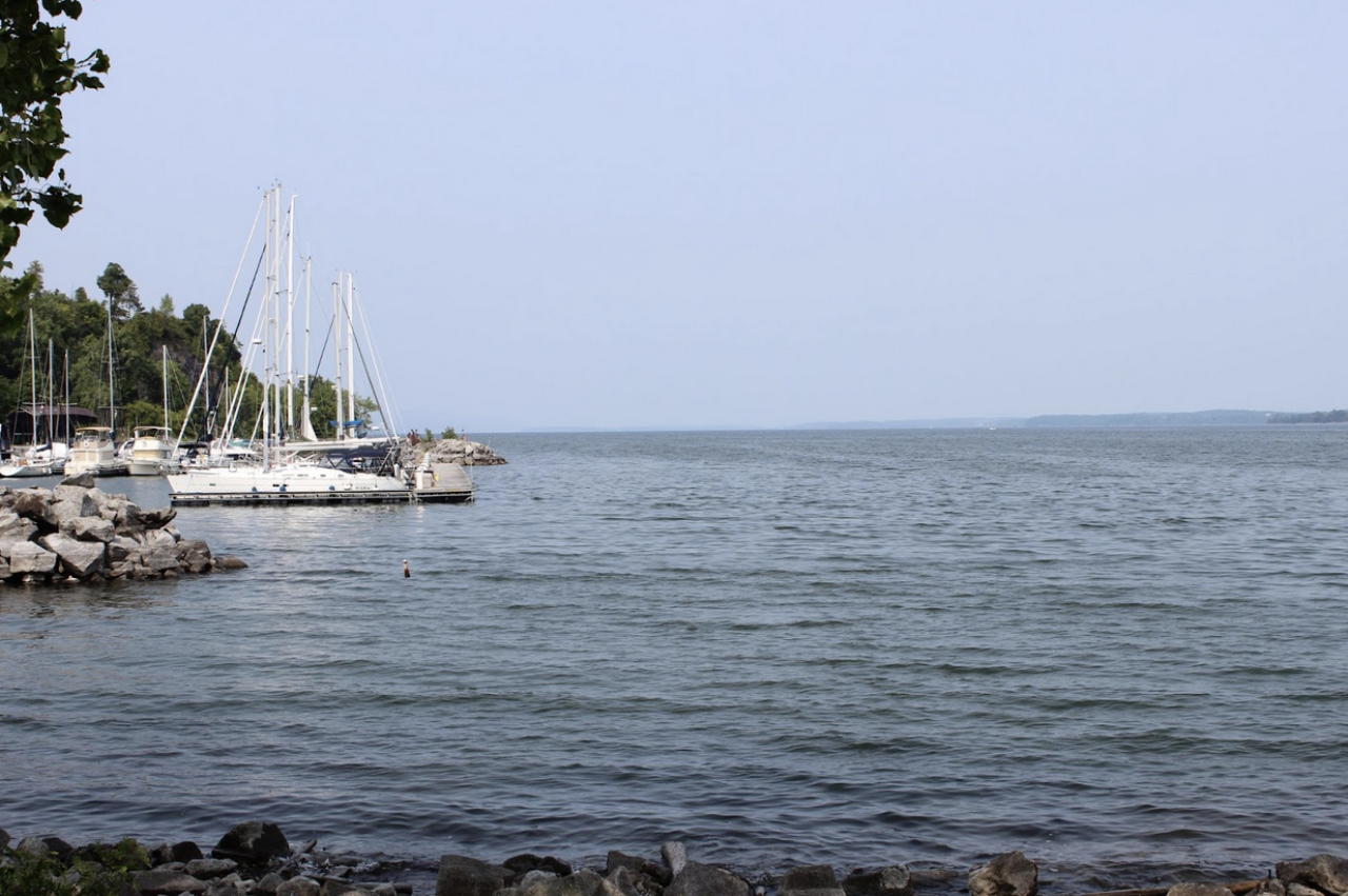Sailboats are moored on the left, with a broad blue lake spreading across the image to the right.