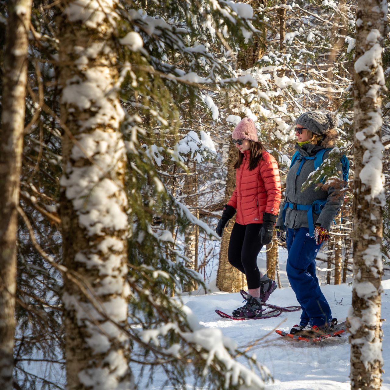 Two women snowshoeing on a snowy trail.