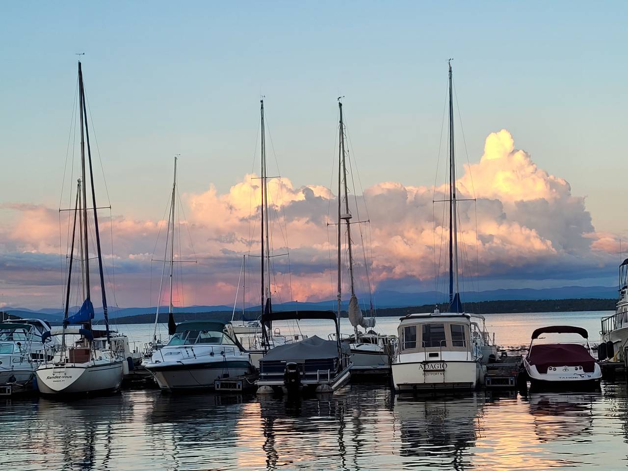 Sailboats lined up at a marina at sunset.
