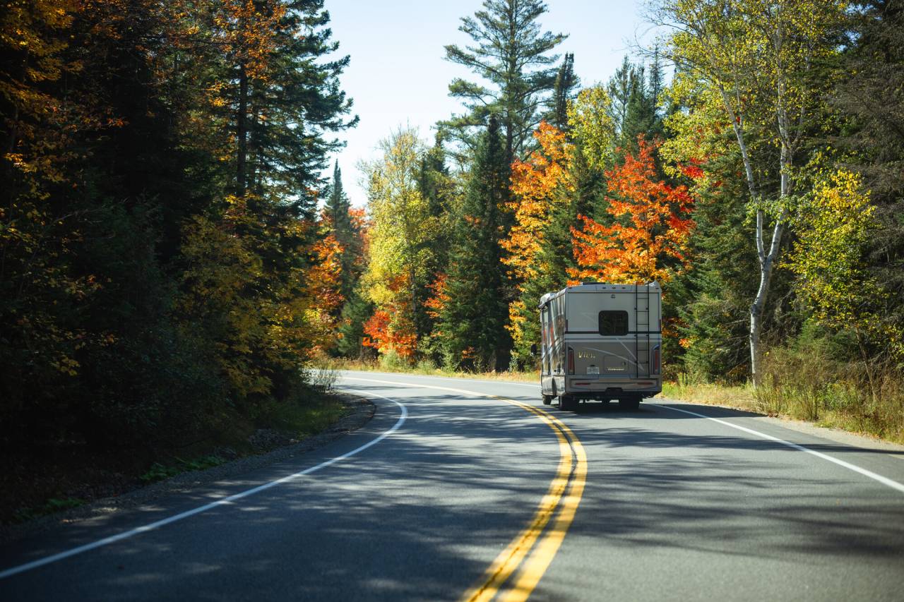 A camper van driving through the Adirondack Hub in the fall.