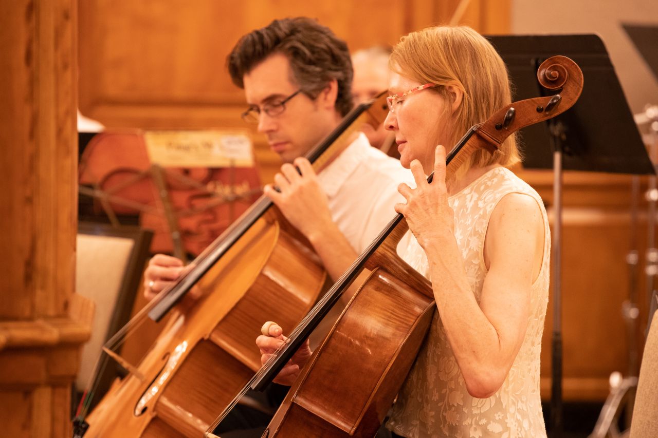 A man and woman play the cello. 