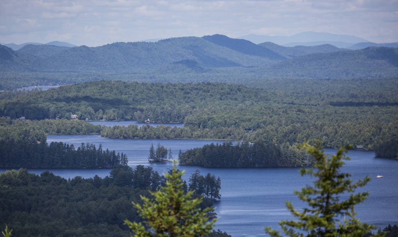 An aerial view of a winding lake surrounded by forest-rich mountains.