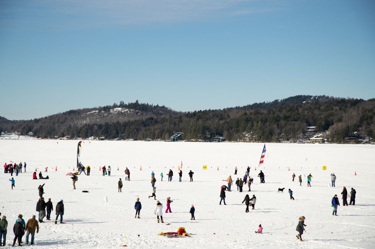 People play games on a frozen lake on a sunny day. 