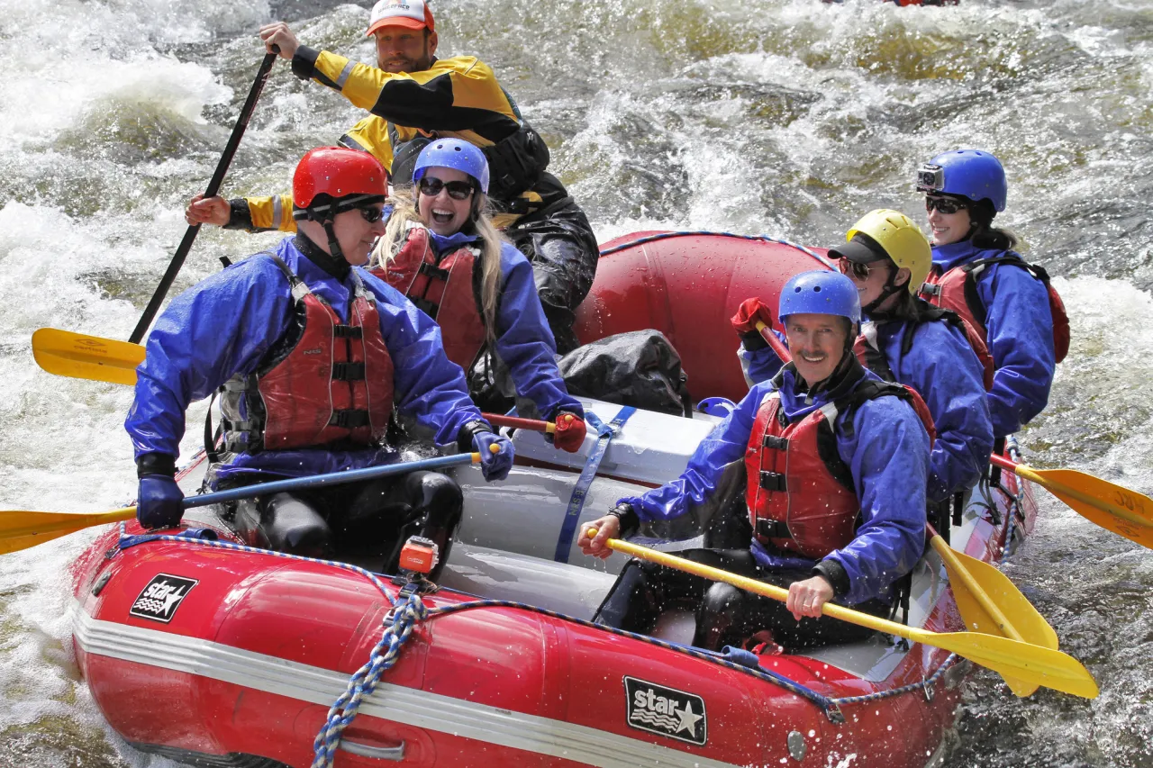 A group of people ride in a raft while whitewater rafting.
