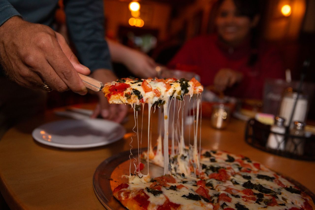 A waiter serves pizza to a table at a restaurant. 