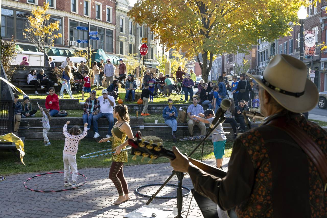 A man plays guitar for a crowd of people dancing in a park.