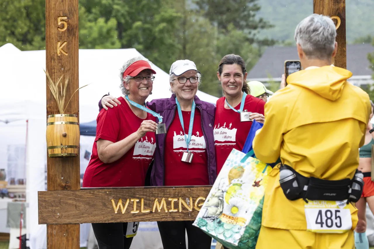 Three women pose for a picture in a picture frame for a race.