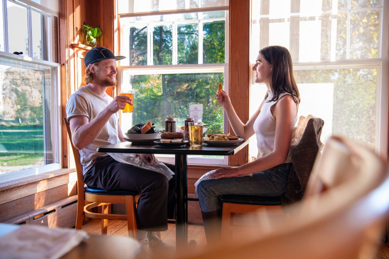 A man and woman dine in a cozy dining room at sunset. 