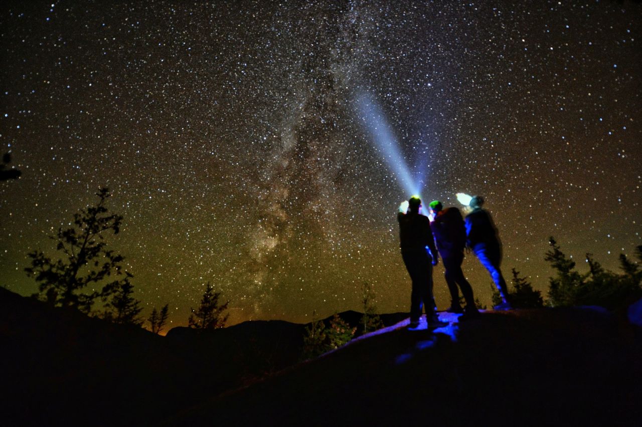 Stargazers on top of a mountain with headlamps