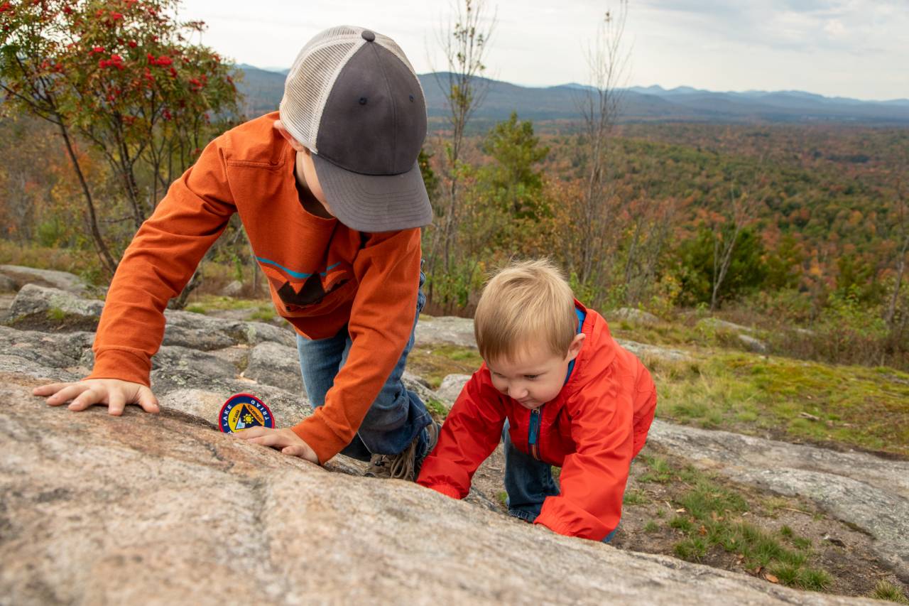Two kids play on a rock