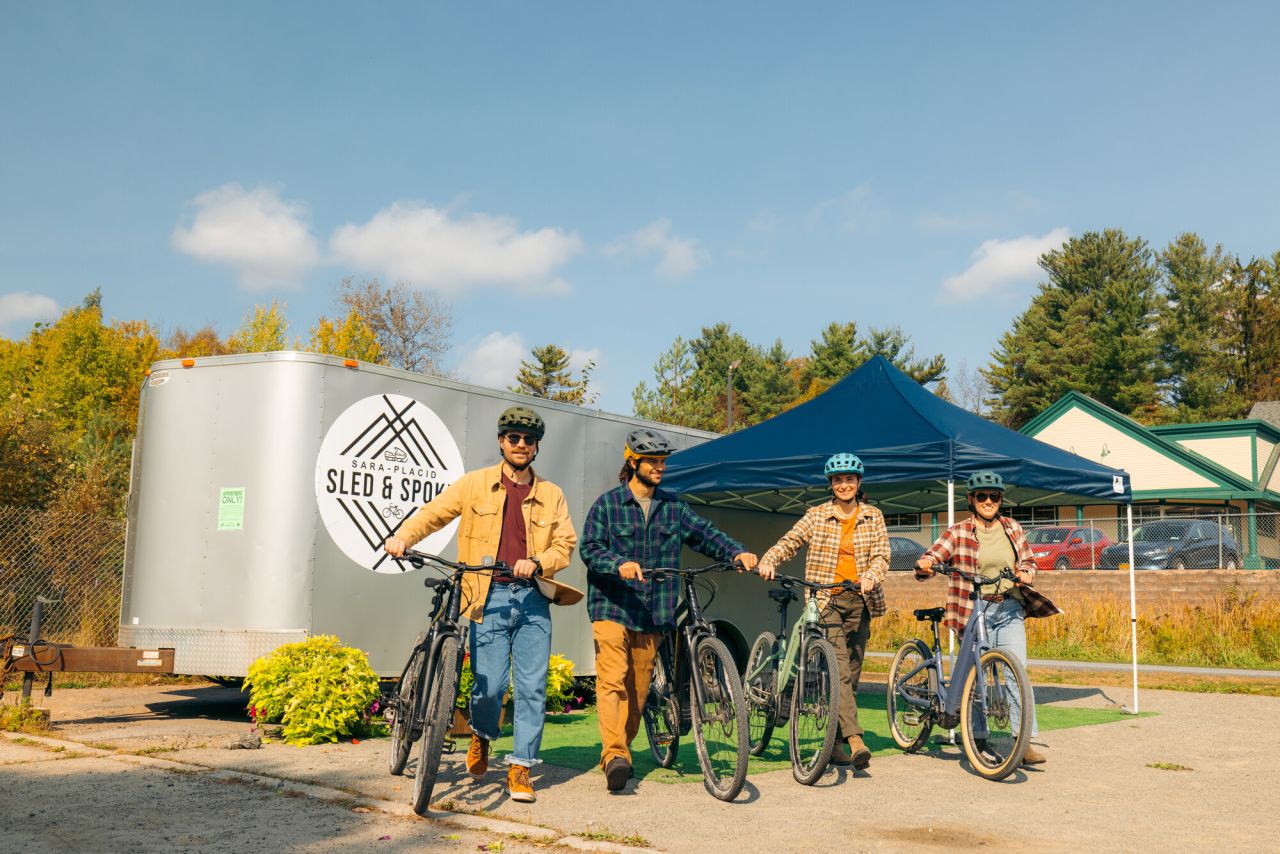 A group of friends get their bikes ready to ride on a fall trail. 