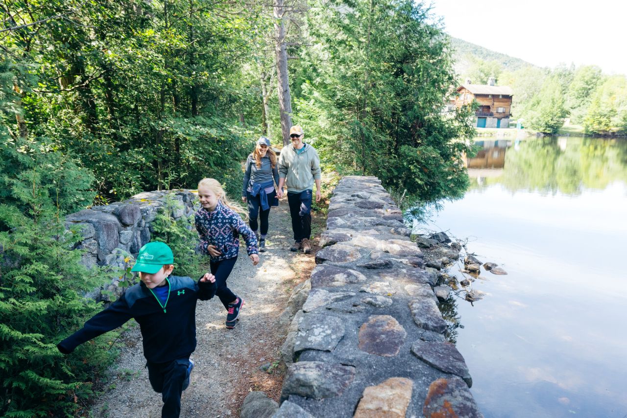 Family walks over stone bridge next to Lake Stevens, with parents holding hands as a young boy and girl run ahead