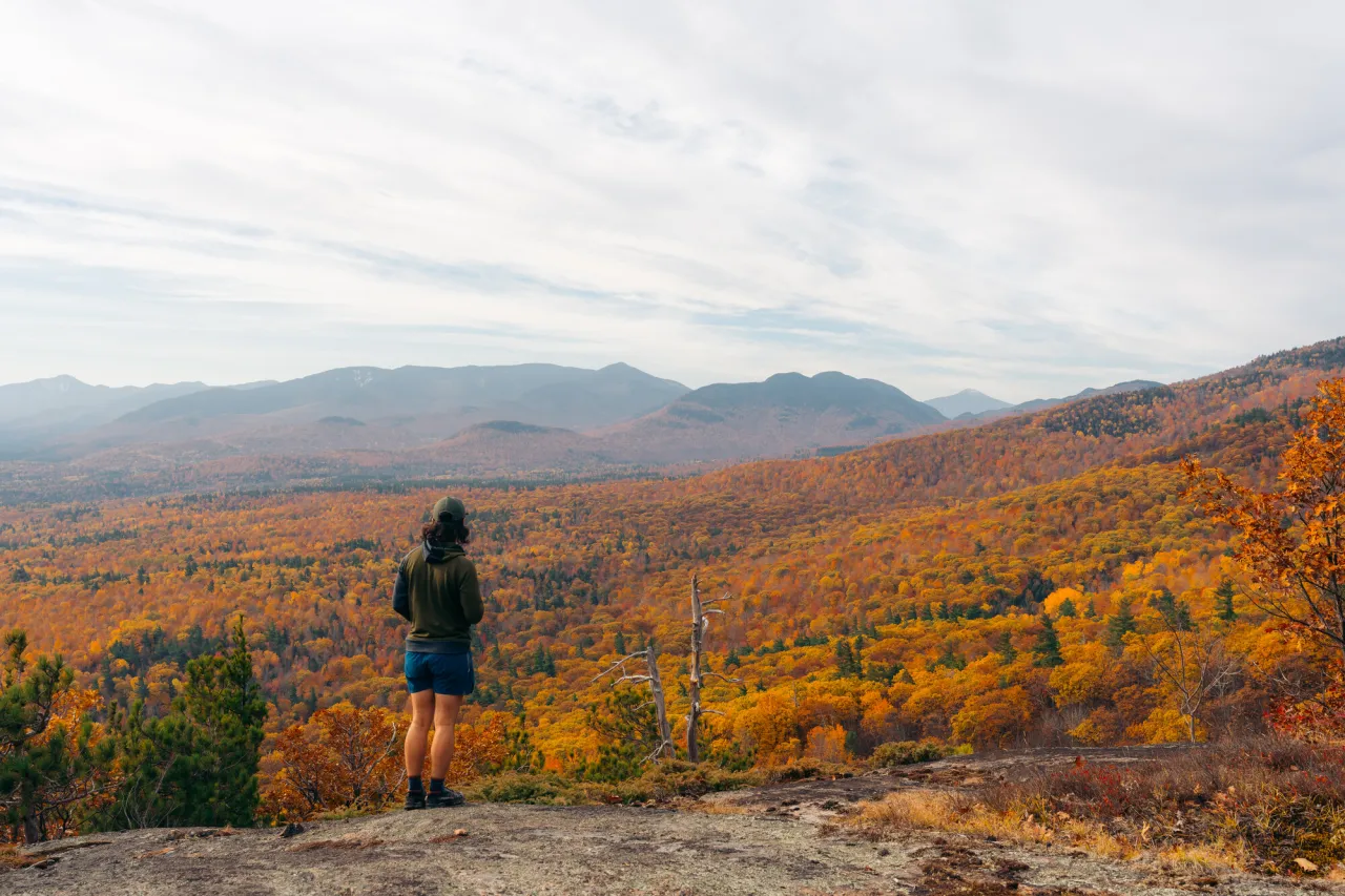 A man stands on a rocky top of a mountain in fall.