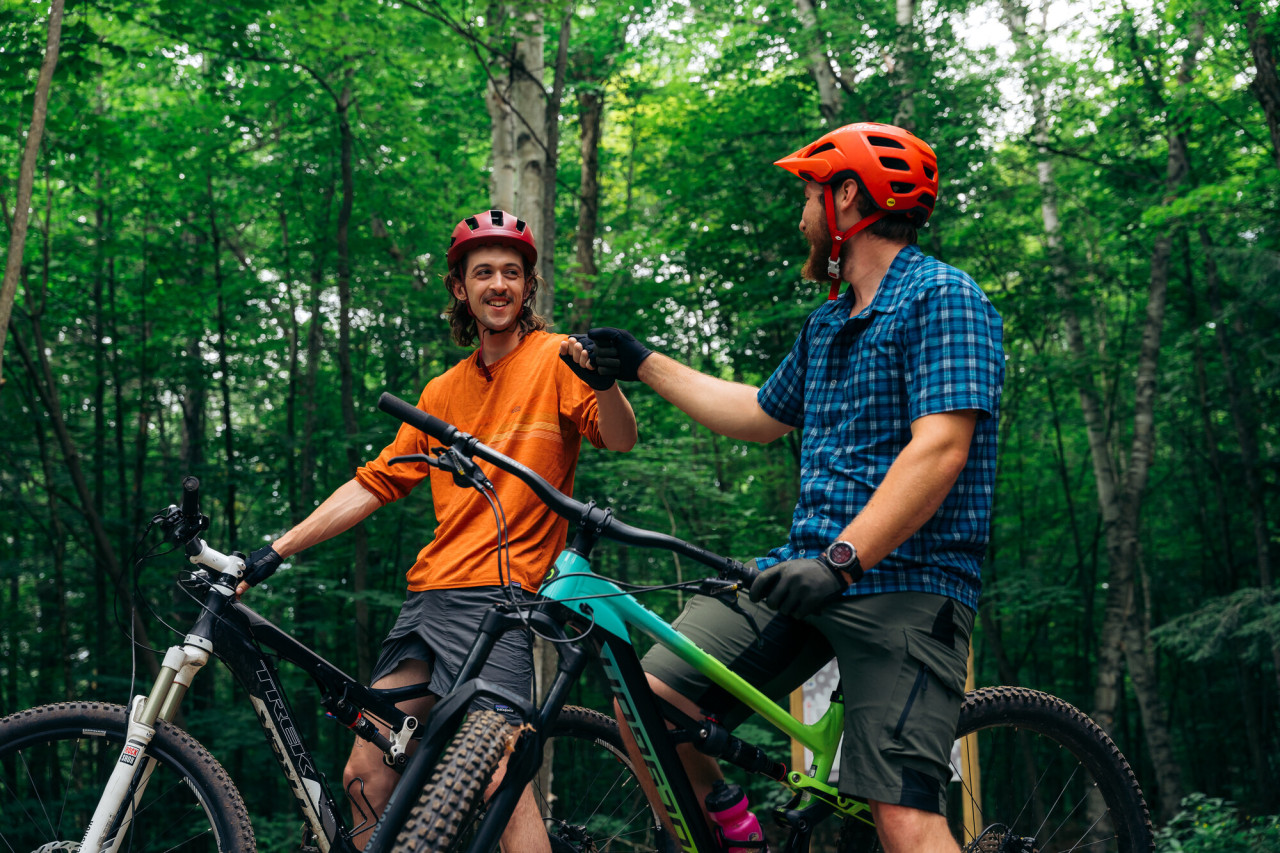 Two bikers chatting in the woods.