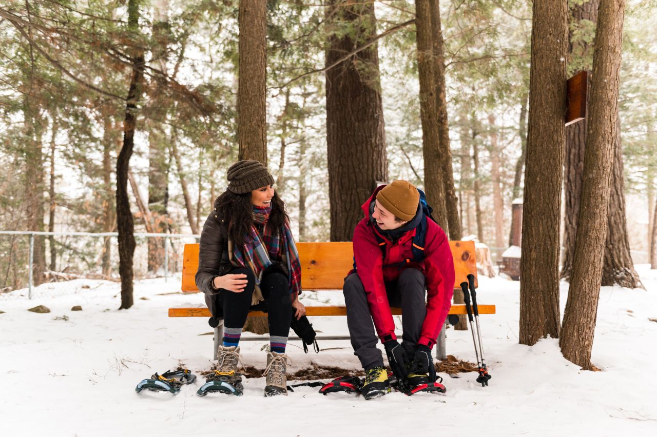 Two people putting on snowshoes.