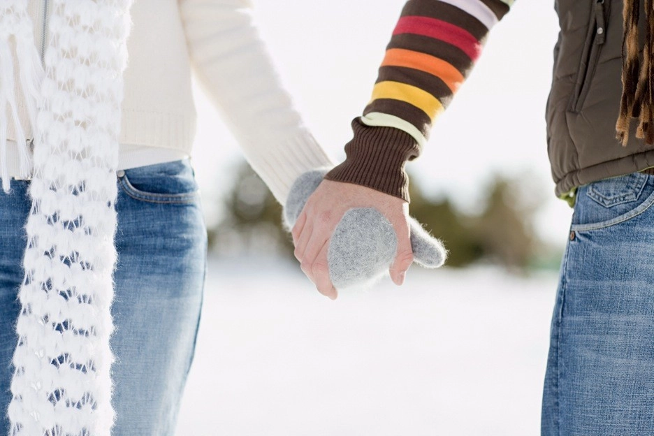 Two mittened hands walk through a snowy meadow