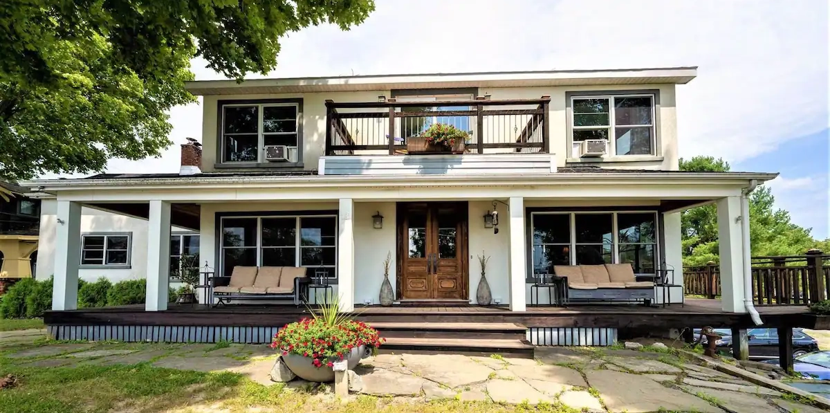Exterior of The Chateau with grand entry onto wrap-around front porch, elevated balcony and comfortable seating options all around
