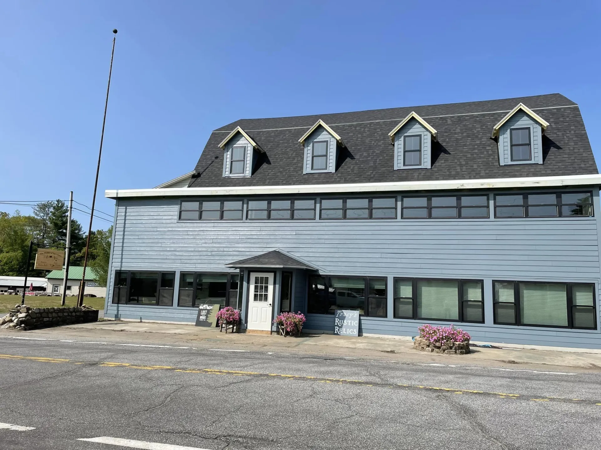 Exterior of a large building with ample parking space an a sign reading Tracy's Rustic Relics