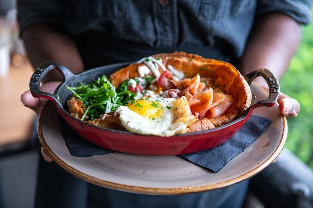 A meal in a wooden bowl with fried egg and greens