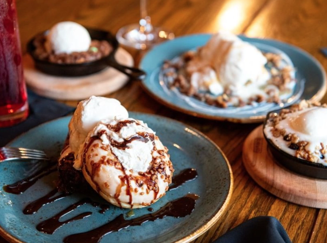 A variety of cakes, cookies, and ice creams drizzled with chocolate.
