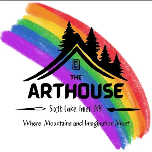 A house roof under pine trees with a rainbow behind and The Arthouse - where mountains and imagination meet