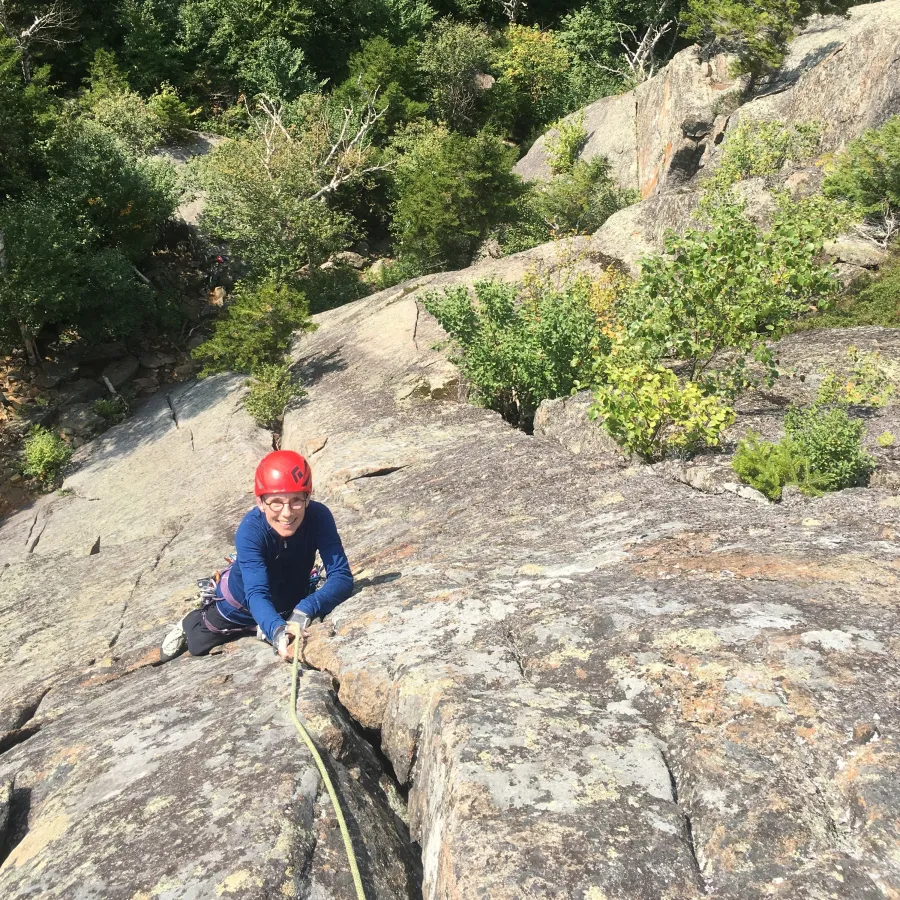 A climber smiles up at the camera