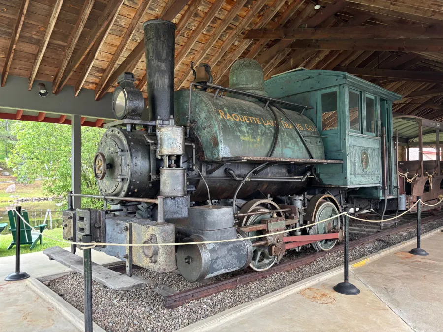 An antique steam engine under a wooden structure